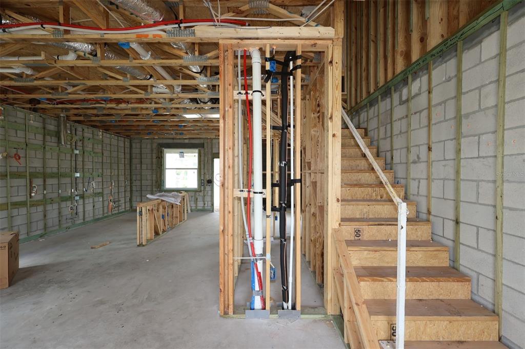 An unfinished room with exposed ceiling joists, concrete block walls, and a stack of drywall — 5294 CENTER LAKE RANCH BOULEVARD, ST CLOUD, FL