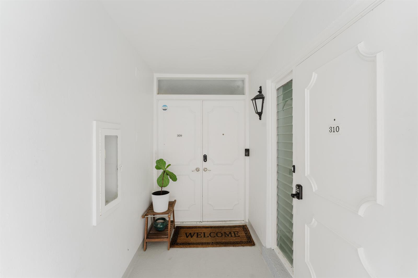 A white-walled entryway features a double door labeled 309, a side door labeled 310, and a plant — 800 E Camino Real # 309, Boca Raton FL 33432, BOCA RATON, FL