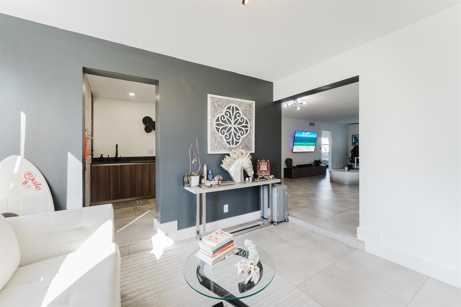 A living area features a gray accent wall, a glass coffee table, and tiled floors — 800 E Camino Real # 309, Boca Raton FL 33432, BOCA RATON, FL