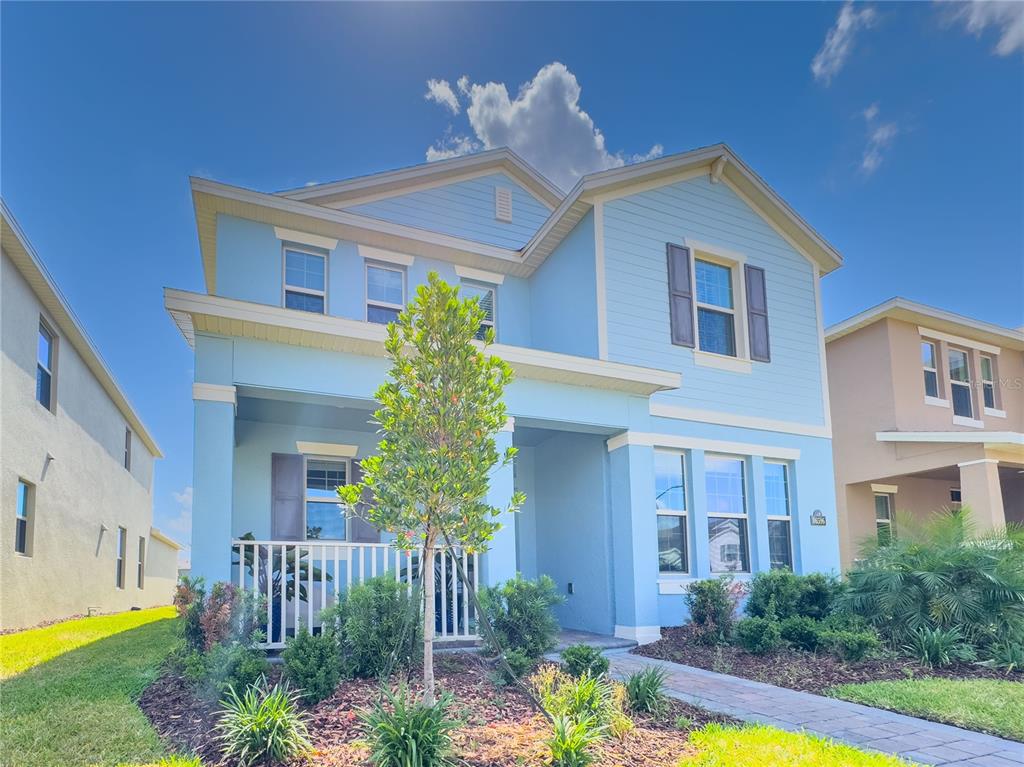 A two-story light blue house with a front porch and a small landscaped yard — 16596 POINT ROCK DRIVE, WINTER GARDEN, FL