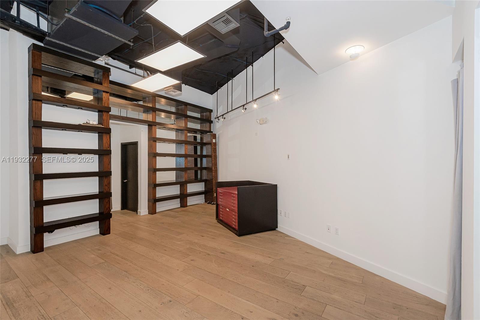 An interior room features light wood flooring, dark open shelving, and a black ceiling — 2030 S Douglas Rd # 120, Coral Gables FL 33134, CORAL GABLES, FL