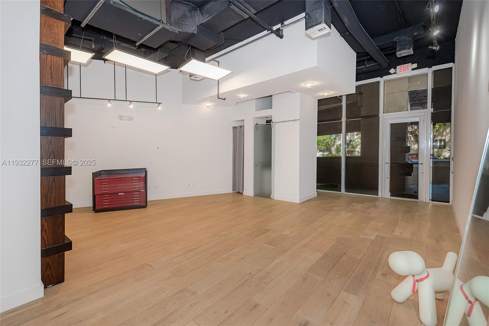 An open commercial space features light wood flooring, exposed black ceilings, and a glass door — 2030 S Douglas Rd # 120, Coral Gables FL 33134, CORAL GABLES, FL