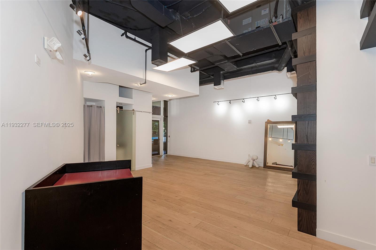 An open commercial space features high ceilings, exposed ductwork, wood flooring, and a large mirror — 2030 S Douglas Rd # 120, Coral Gables FL 33134, CORAL GABLES, FL