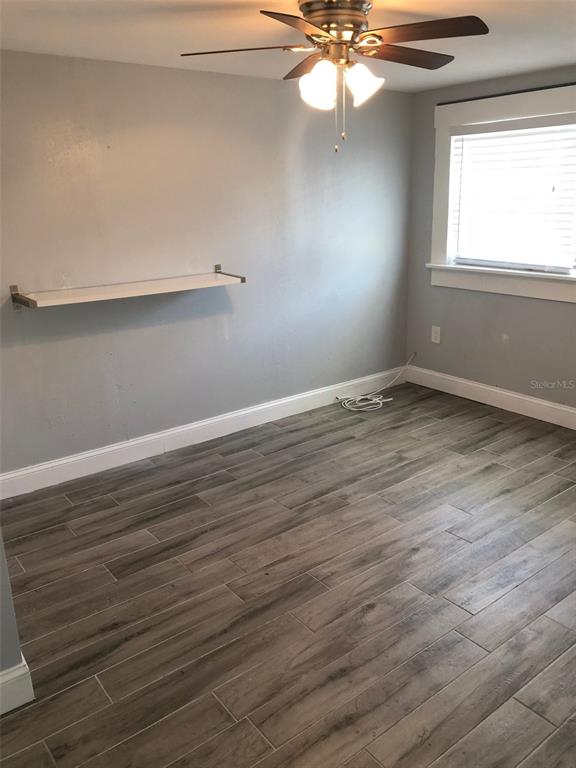 An empty room features gray walls, wood-look tile flooring, a ceiling fan, and a wall shelf — 216 12TH AVENUE N UNIT Downstairs, ST PETERSBURG, FL