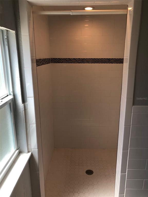 A walk-in shower features white subway tile walls, a dark accent border, and a tiled floor — 216 12TH AVENUE N UNIT Downstairs, ST PETERSBURG, FL