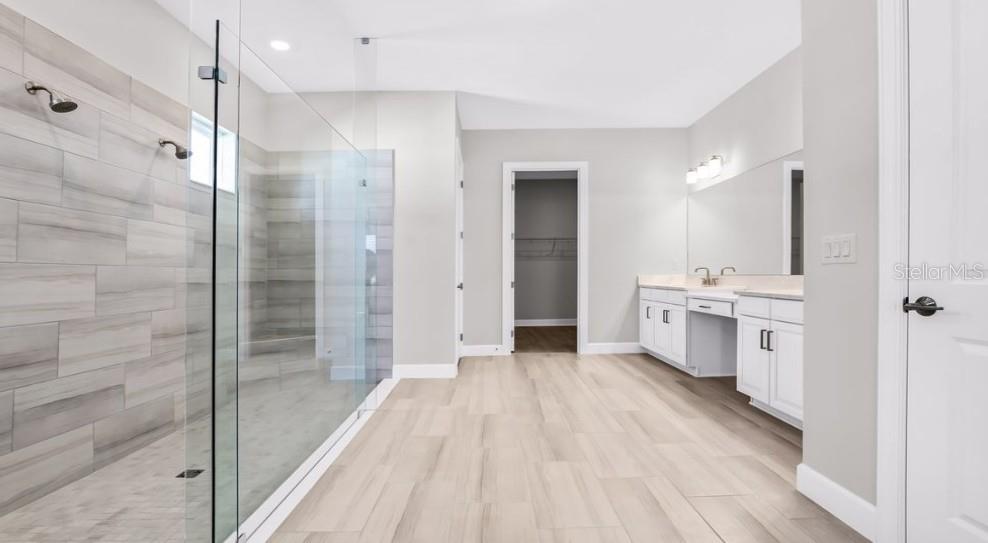A modern bathroom features a glass-enclosed walk-in shower, white cabinetry, and light-colored tile flooring — 26909 VICTORIA PLACE, PUNTA GORDA, FL