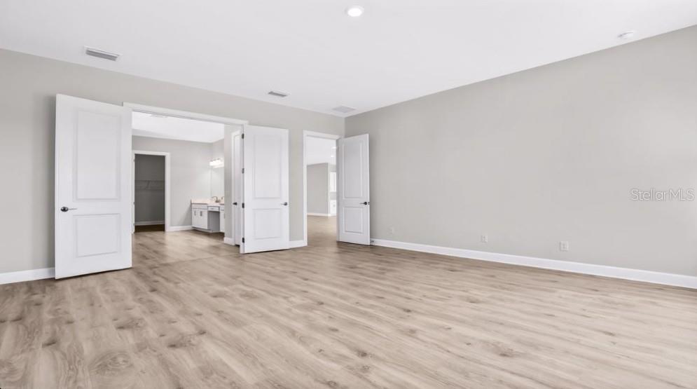 A spacious room with light wood-look flooring, gray walls, and multiple white interior doors — 26909 VICTORIA PLACE, PUNTA GORDA, FL