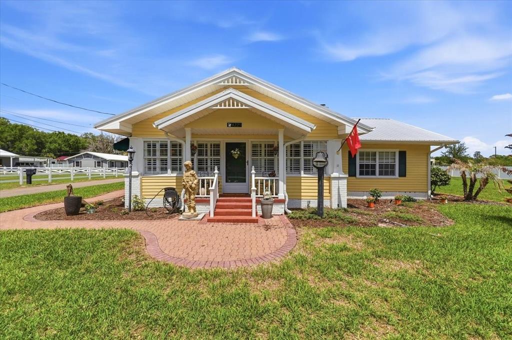 A yellow single-story house with a front porch, brick steps, and a paved walkway — 4225 OLD KATHLEEN ROAD, LAKELAND, FL
