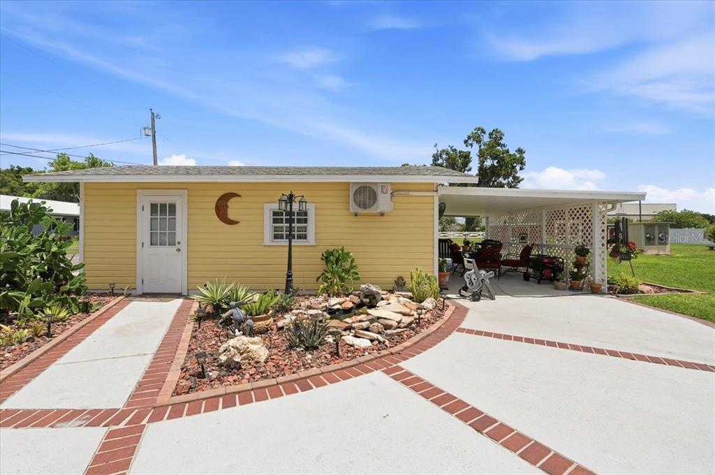 A yellow house with a white door, a carport, and a landscaped rock garden — 4225 OLD KATHLEEN ROAD, LAKELAND, FL