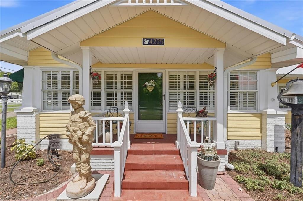 A yellow house with a front porch, a soldier statue, and a brick walkway — 4225 OLD KATHLEEN ROAD, LAKELAND, FL