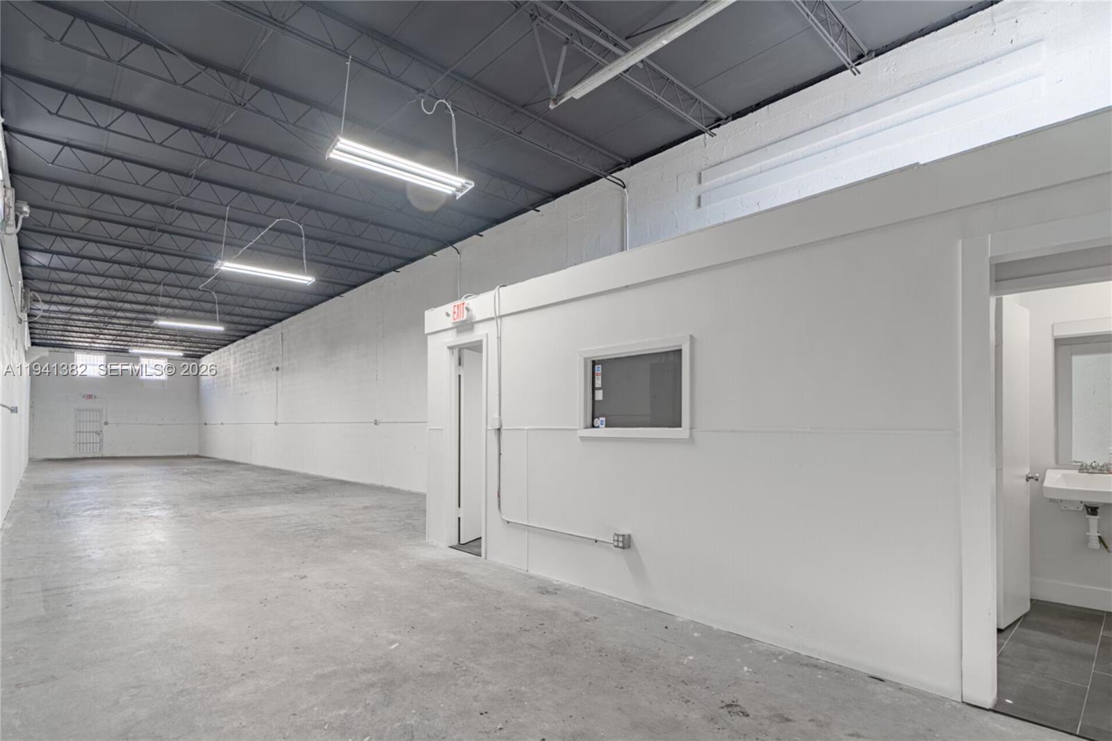 An industrial warehouse space features a concrete floor, exposed ceiling, and a small enclosed office — 569 W 28th St, Hialeah FL 33010, HIALEAH, FL