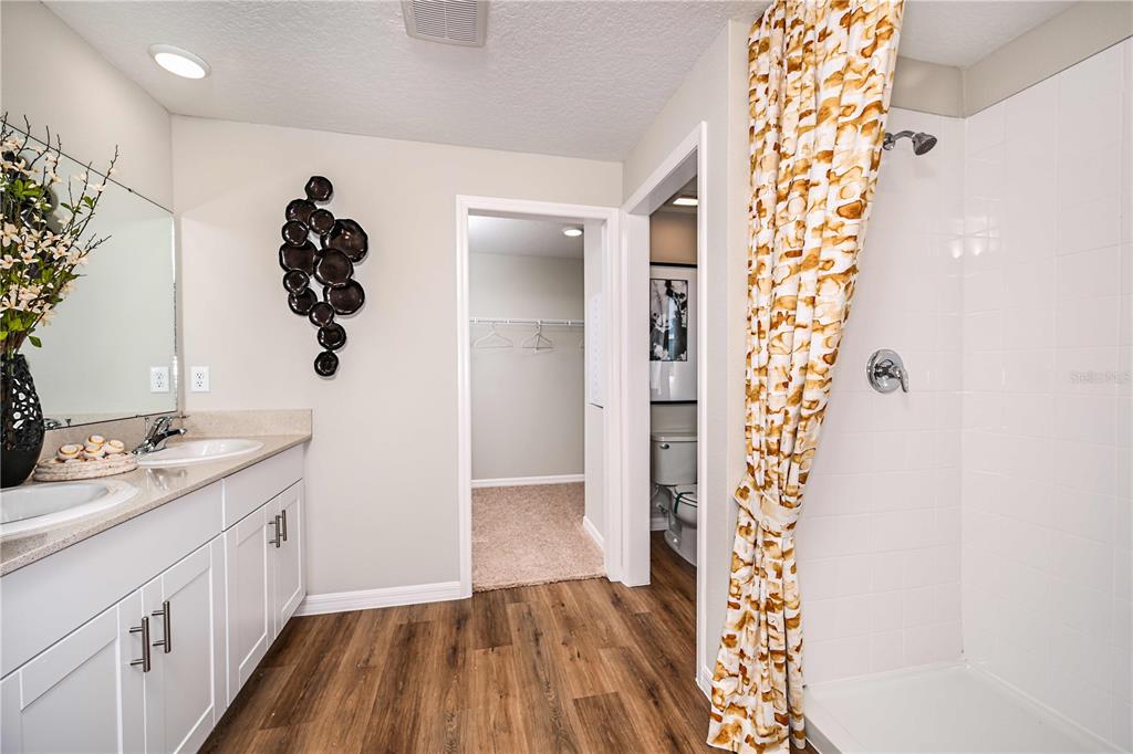A bathroom features a double vanity, a walk-in closet, and a tiled shower with patterned curtains — 4156 RIVER BEACON BOULEVARD, DAVENPORT, FL