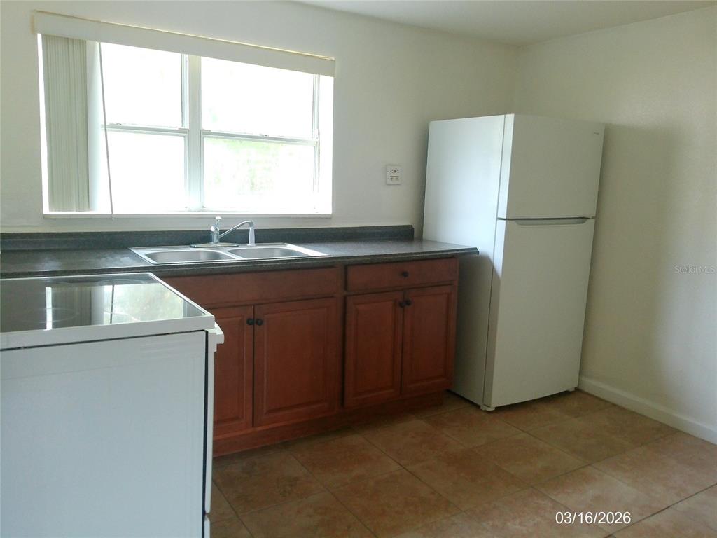 A kitchen features wooden cabinets, a dark countertop, a stainless steel sink, and a refrigerator — 808 S CENTRAL AVENUE S, LAKELAND, FL