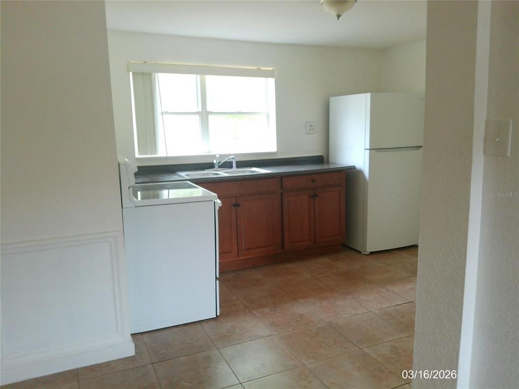 A kitchen features wood cabinets, a white stove, a white refrigerator, and tile flooring — 808 S CENTRAL AVENUE S, LAKELAND, FL