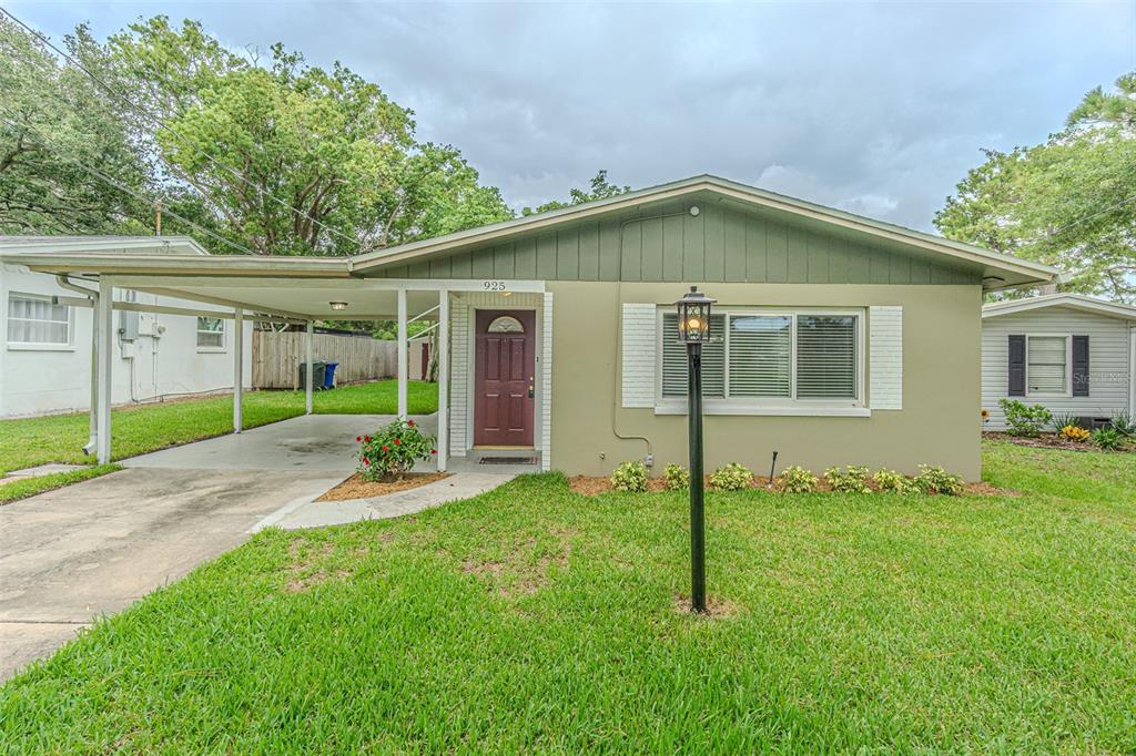 A single-story house with a carport, green siding, and a red front door — 925 CEDARWOOD AVENUE, DUNEDIN, FL