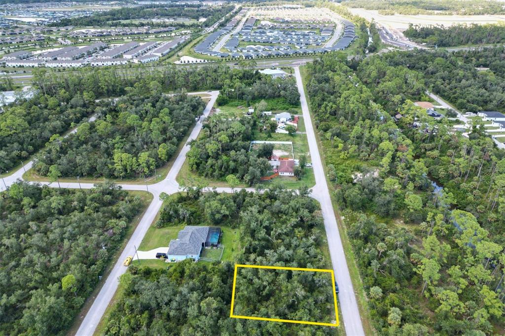 An aerial view shows a rectangular, wooded vacant lot outlined in yellow next to a road — 2157 TEA STREET, PORT CHARLOTTE, FL
