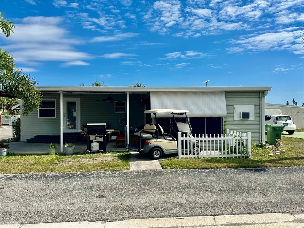A light green manufactured home with a covered porch, a golf cart, and a white fence — 2503 16TH STREET W, BRADENTON, FL