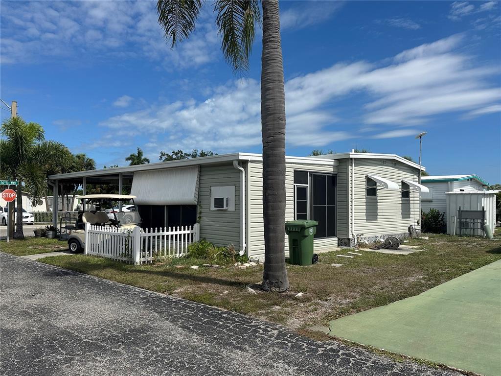 A light green mobile home features a covered carport, a golf cart, and a palm tree — 2503 16TH STREET W, BRADENTON, FL