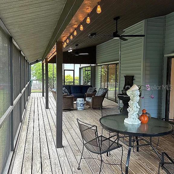 A screened-in porch features a wooden deck, outdoor furniture, and string lights — 881 PINTO CIRCLE, NOKOMIS, FL