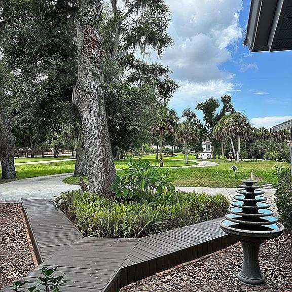 A tiered fountain stands beside a wooden walkway leading to a landscaped tree area — 881 PINTO CIRCLE, NOKOMIS, FL