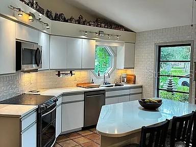 A kitchen with white cabinets, stainless steel appliances, a center island, and a large window — 881 PINTO CIRCLE, NOKOMIS, FL