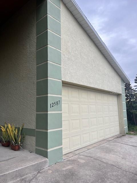 A beige stucco house exterior features a white garage door and green corner trim — 12587 PARK BOULEVARD, SEMINOLE, FL