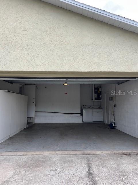 An open garage features a concrete floor, white walls, and a laundry area with appliances — 12587 PARK BOULEVARD, SEMINOLE, FL