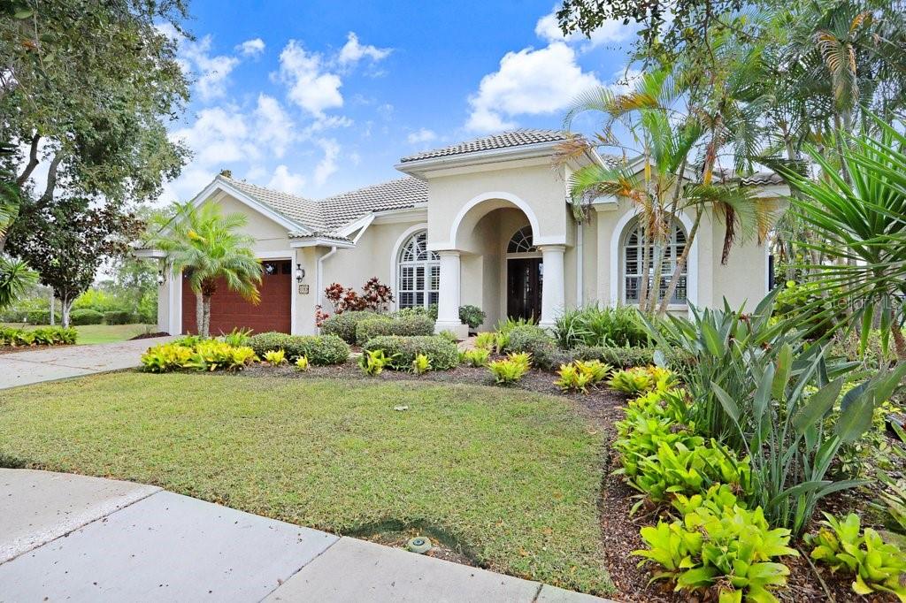 A single-story house with a beige stucco exterior, a tiled roof, and a landscaped yard — 1161 MARINA DRIVE, TARPON SPRINGS, FL