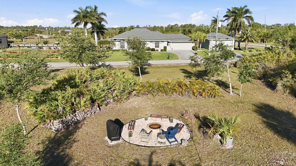 An aerial view shows a backyard fire pit area with seating and a nearby house — 8050 TRACY CIRCLE, PORT CHARLOTTE, FL