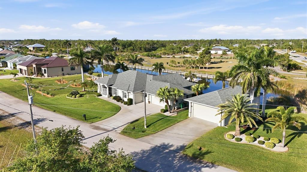 An aerial view shows a single-story house with a gray roof and a detached garage — 8050 TRACY CIRCLE, PORT CHARLOTTE, FL
