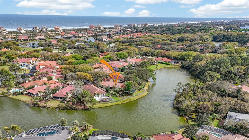 A grassy backyard features a metal fence overlooking a pond surrounded by trees — 11 LAGUNA COURT, PALM COAST, FL