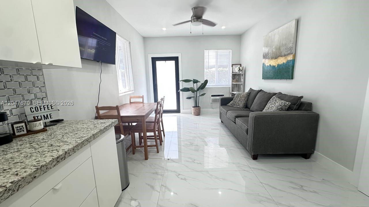 A living and dining area features white tile floors, a gray sofa, and a wooden table — 320 SW 29th Rd, Miami FL 33129, MIAMI, FL
