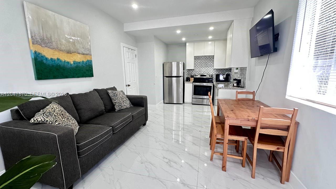 A living room with a gray sofa and a kitchen with white cabinets and appliances — 320 SW 29th Rd, Miami FL 33129, MIAMI, FL