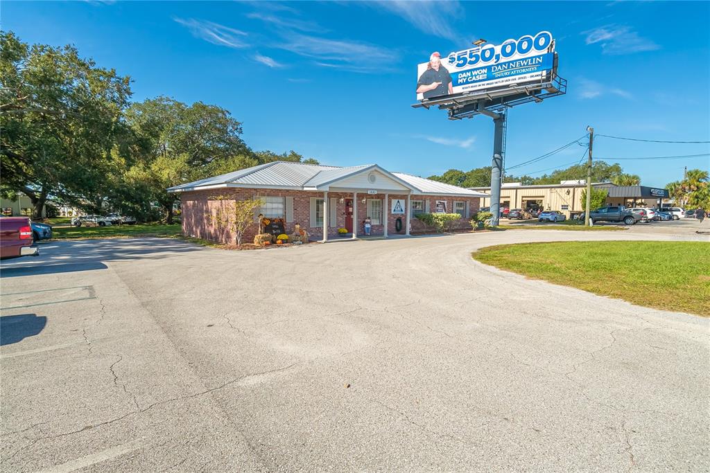 A single-story brick commercial building sits on a paved lot beneath a large billboard — 1680 IRLO BRONSON MEMORIAL HIGHWAY, KISSIMMEE, FL
