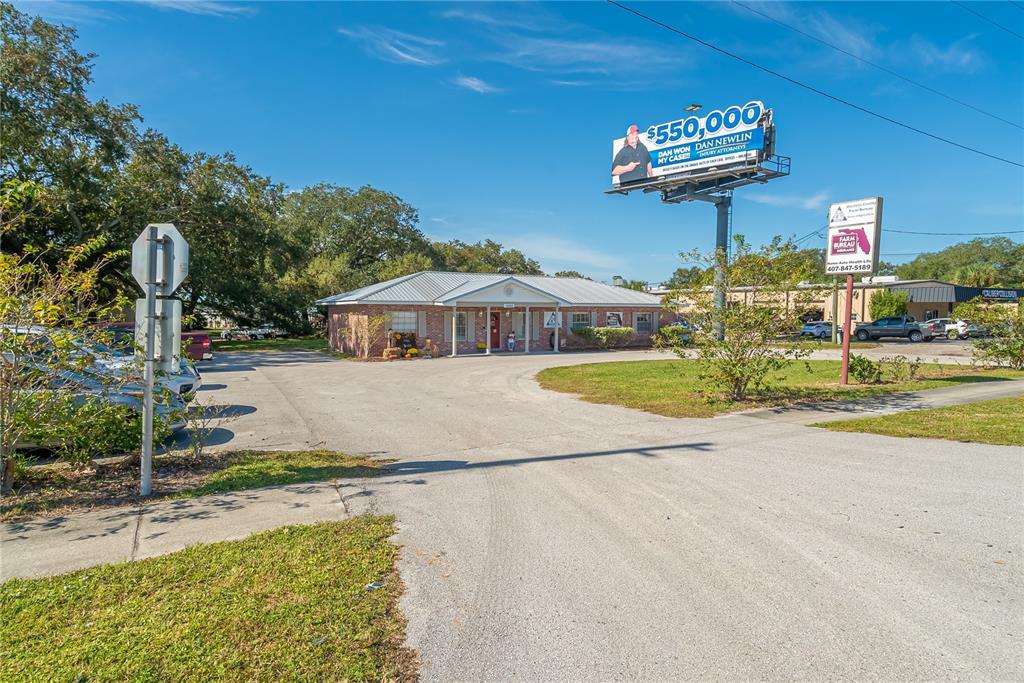 A single-story brick building with a metal roof sits behind a parking lot and billboard — 1680 IRLO BRONSON MEMORIAL HIGHWAY, KISSIMMEE, FL