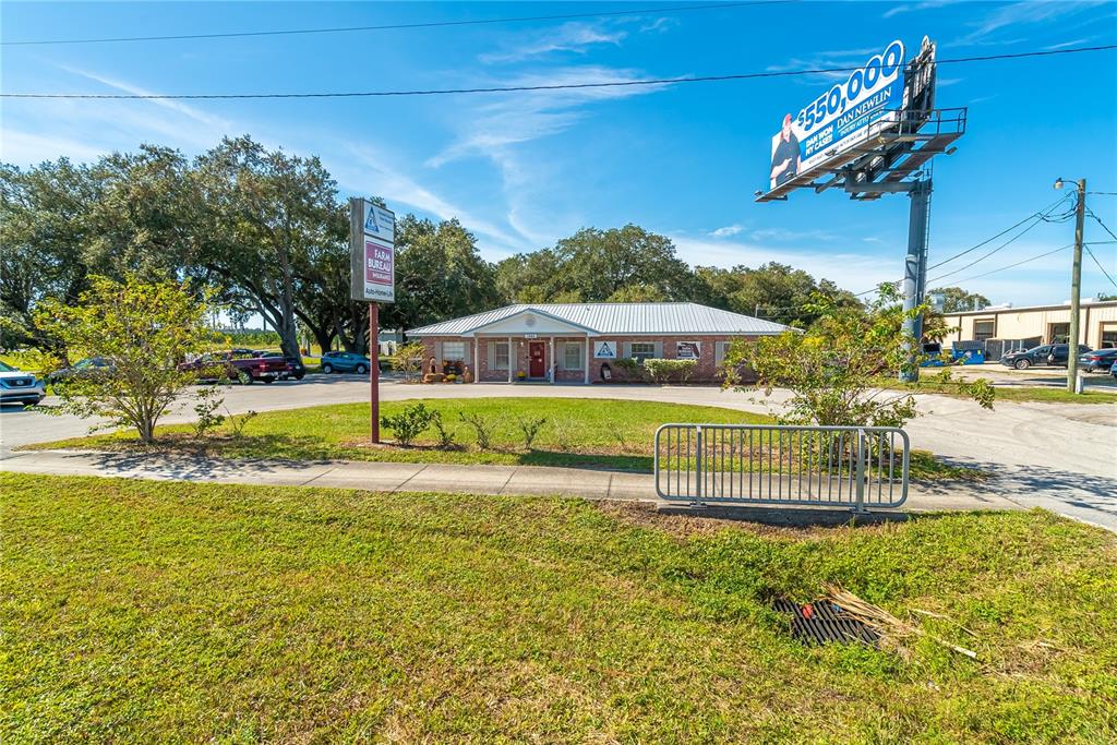 A single-story brick office building sits behind a parking lot with a large billboard nearby — 1680 IRLO BRONSON MEMORIAL HIGHWAY, KISSIMMEE, FL