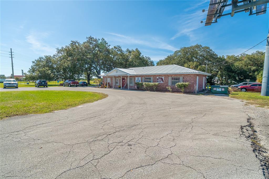 A single-story brick commercial building sits behind a large, cracked asphalt parking lot — 1680 IRLO BRONSON MEMORIAL HIGHWAY, KISSIMMEE, FL