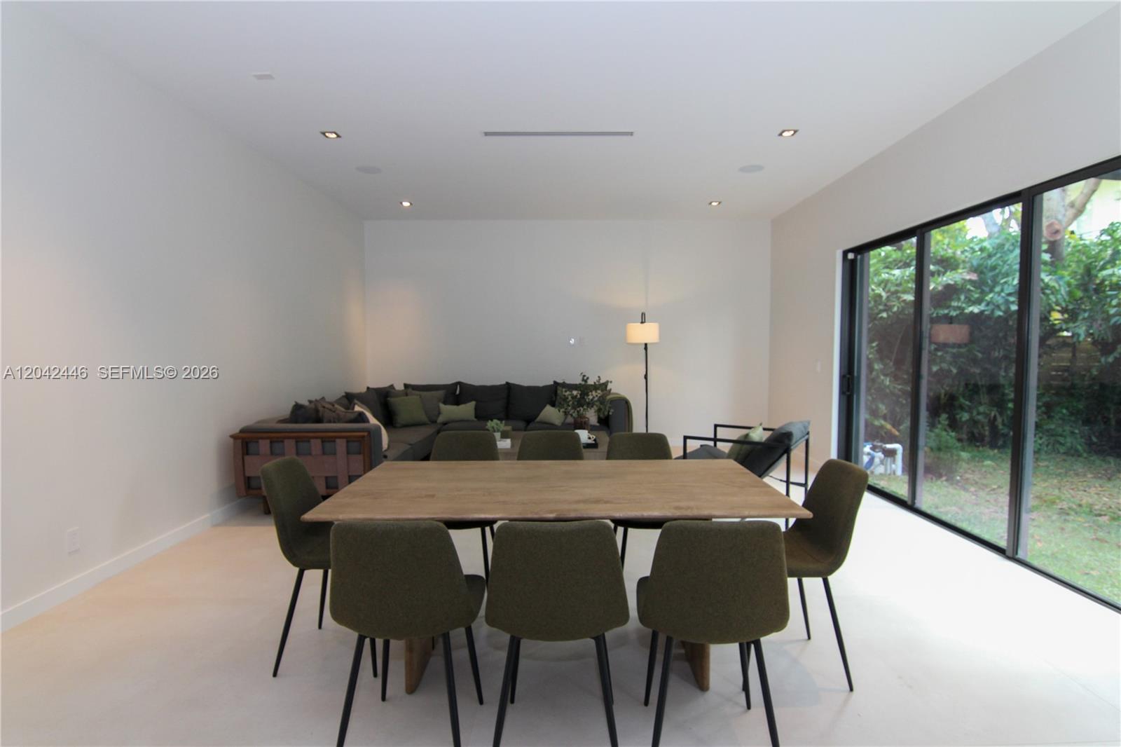A dining area with a wooden table and olive chairs sits before a living room — 3540 Oak Ave, Miami FL 33133, MIAMI, FL