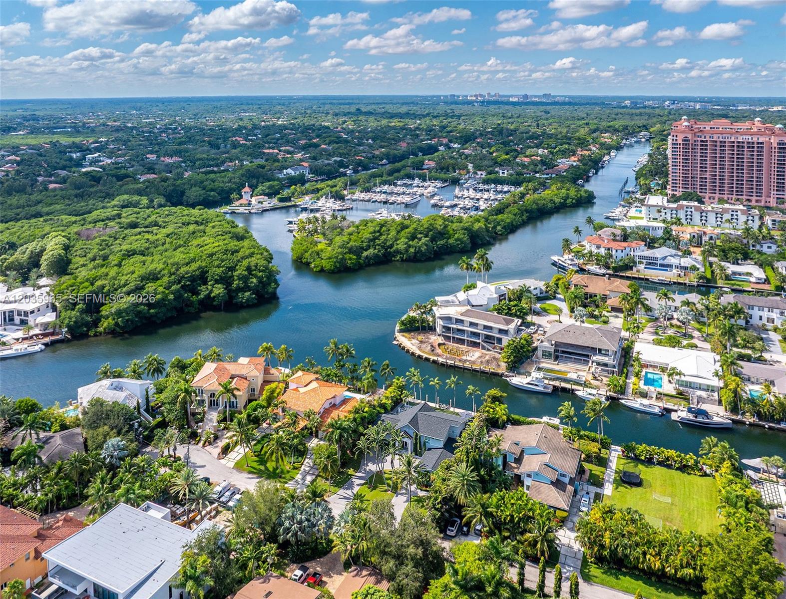 An aerial view shows luxury waterfront homes, a marina, and dense vegetation along a canal — 6944 Sunrise Ter, Coral Gables FL 33133, CORAL GABLES, FL