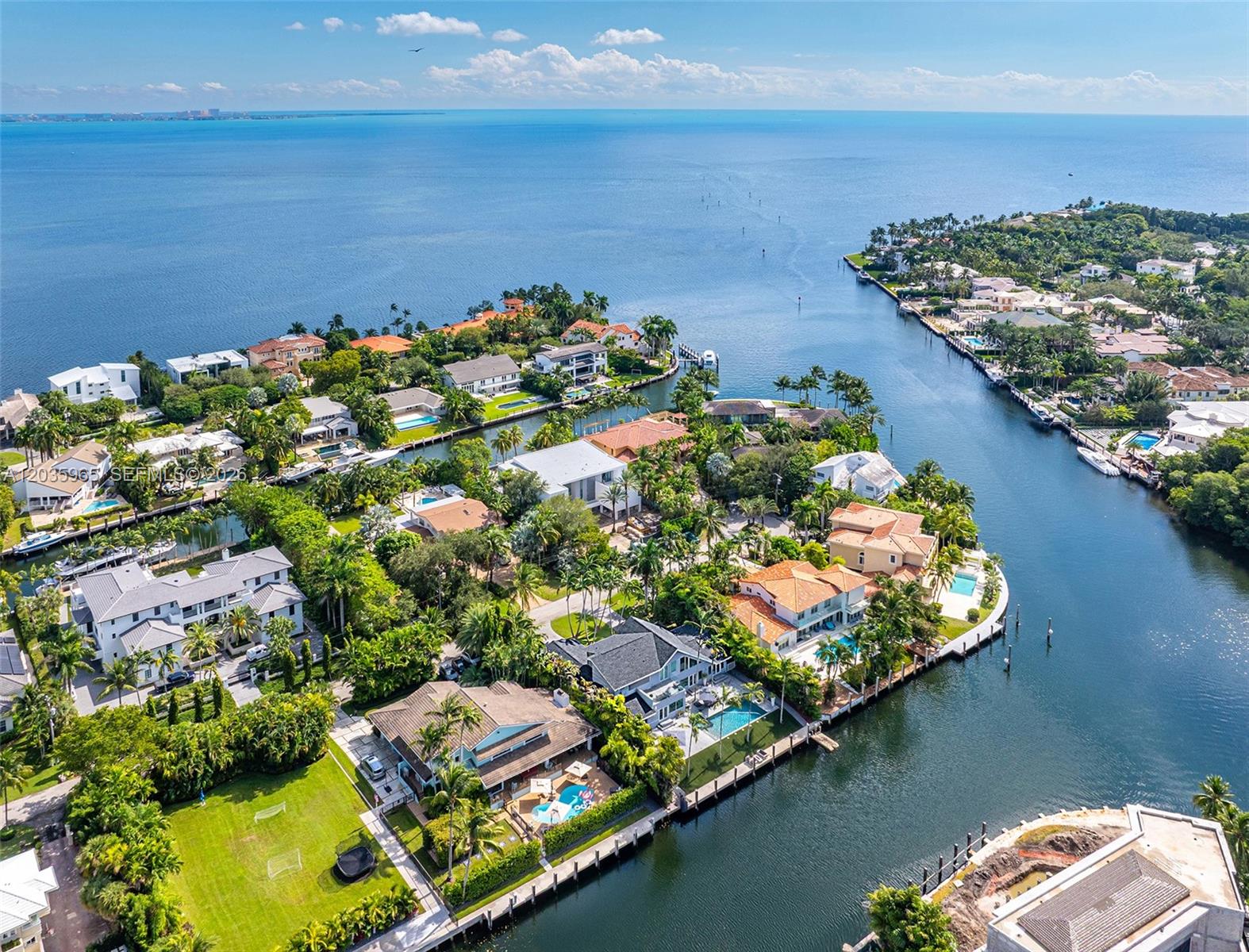 An aerial view shows luxury waterfront homes with swimming pools along a canal and bay — 6944 Sunrise Ter, Coral Gables FL 33133, CORAL GABLES, FL