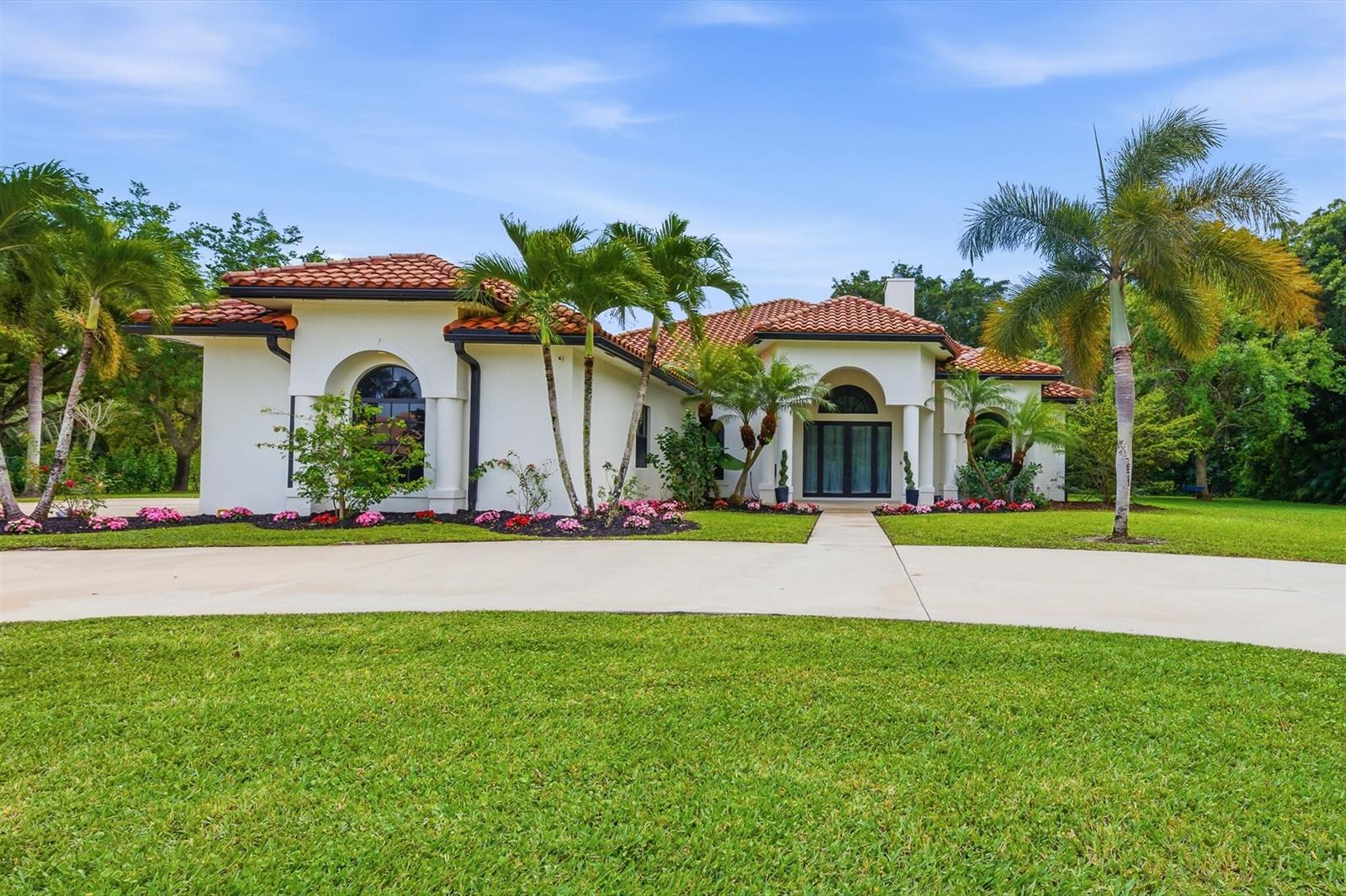 A bright living room features light wood floors, three large wall mirrors, and patio access — 8717 Estate Drive, West Palm Beach FL 33411, WEST PALM BEACH, FL