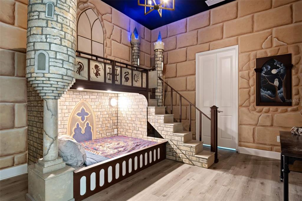 A themed bedroom features a castle-style bunk bed with stone-textured walls and a staircase — 4041 SONOMA BOULEVARD, KISSIMMEE, FL