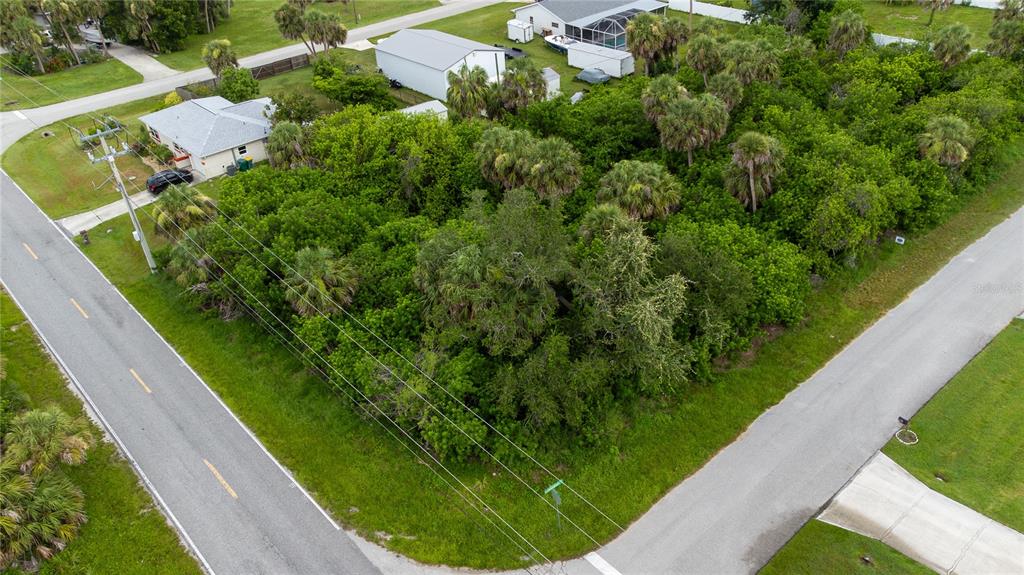 An aerial view shows a vacant, heavily wooded corner lot situated between two paved roads — 18390 OHARA DRIVE, PORT CHARLOTTE, FL