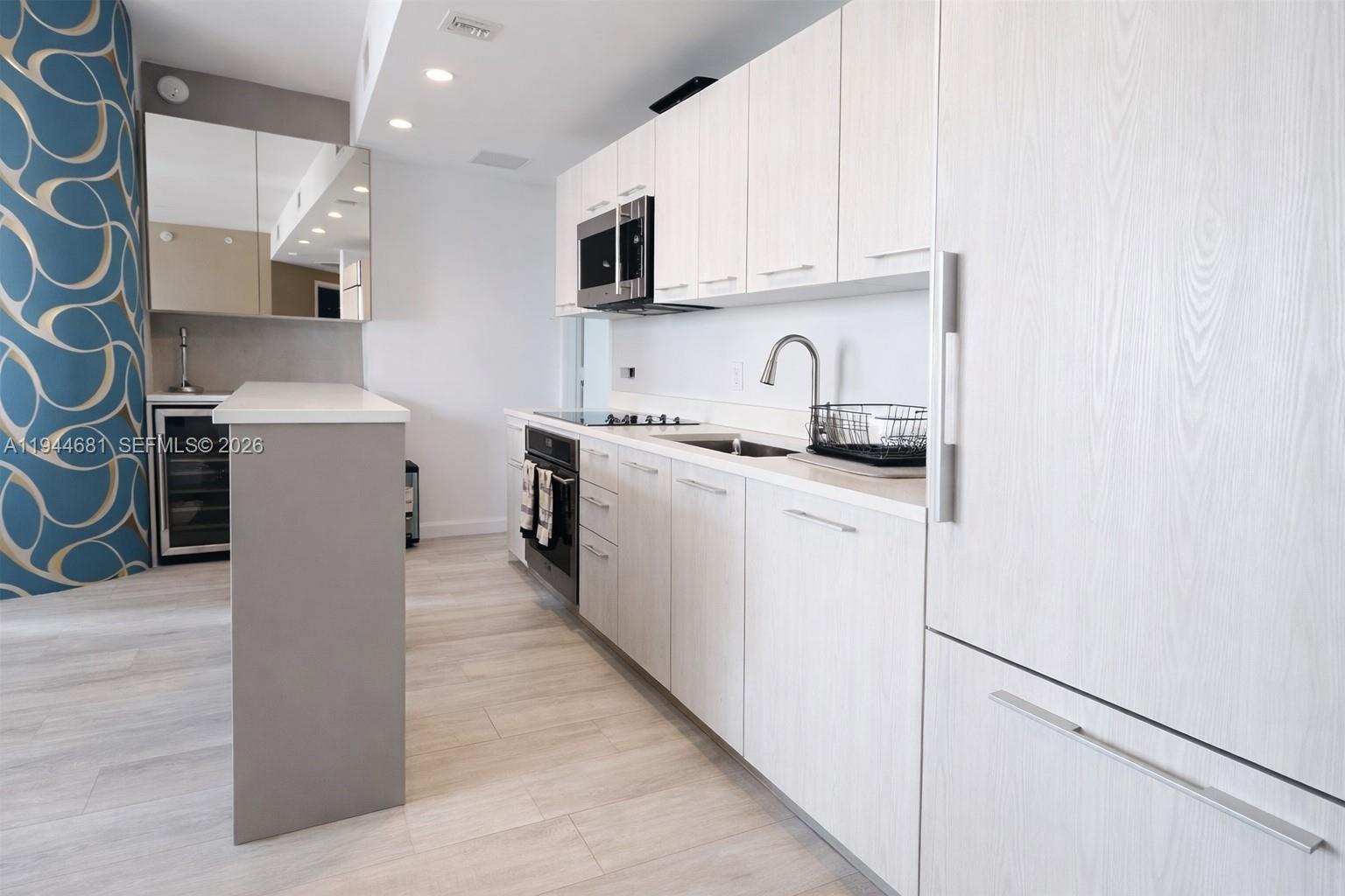 A modern kitchen features light wood-grain cabinetry, white countertops, and a blue patterned accent wall — 45 SW 9th St # 3008, Miami FL 33130, MIAMI, FL