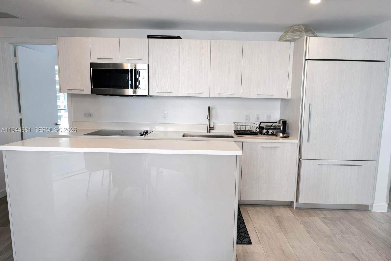 A modern kitchen features light wood-grain cabinets, white countertops, stainless steel appliances, and an island — 45 SW 9th St # 3008, Miami FL 33130, MIAMI, FL