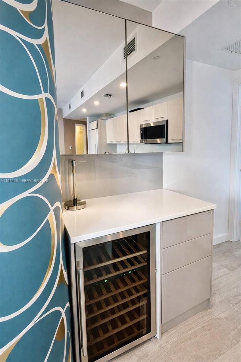 A wet bar area features a wine cooler, white countertop, and mirrored upper cabinets — 45 SW 9th St # 3008, Miami FL 33130, MIAMI, FL