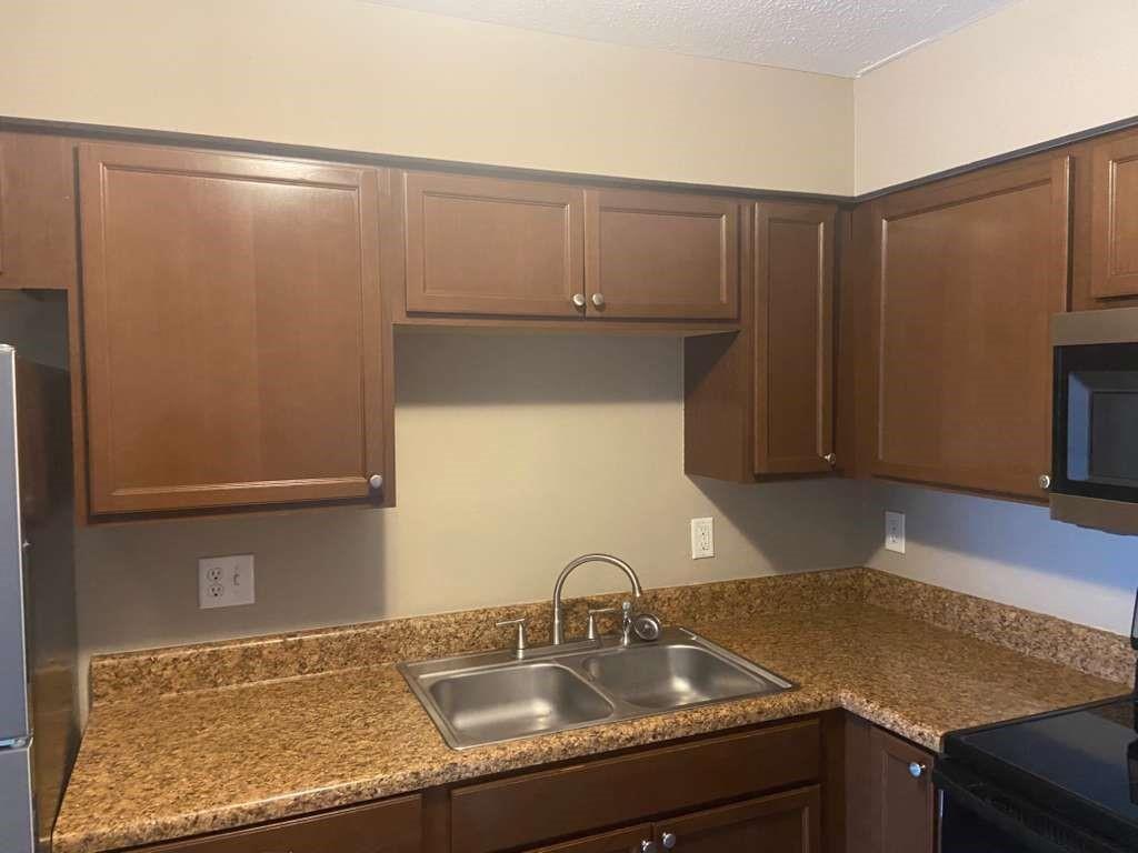 A kitchen features brown cabinets, granite-look countertops, a double-basin sink, and a microwave — 1801 SE 40th Street Road, Ocala FL 34480, OCALA, FL