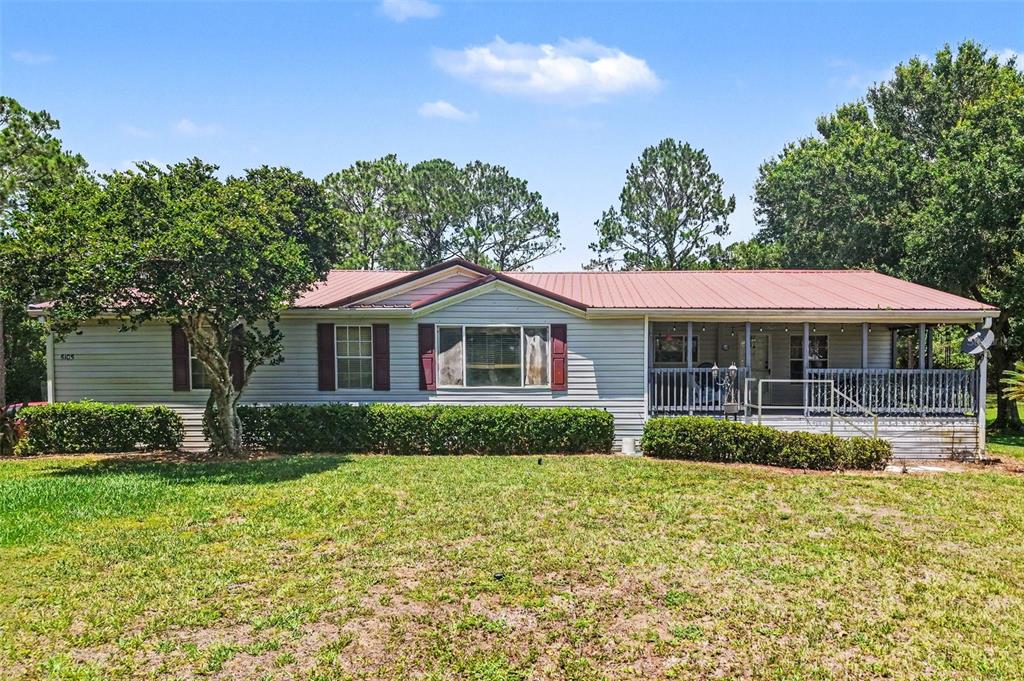 A single-story house with light siding, a red metal roof, and a front porch — 5105 STAR LINE DRIVE, ST CLOUD, FL