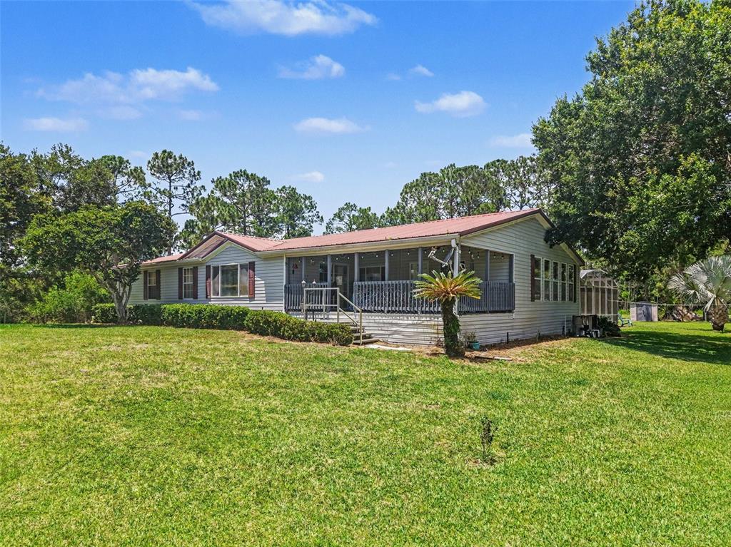 A single-story house with a metal roof and a screened-in porch sits on a lawn — 5105 STAR LINE DRIVE, ST CLOUD, FL