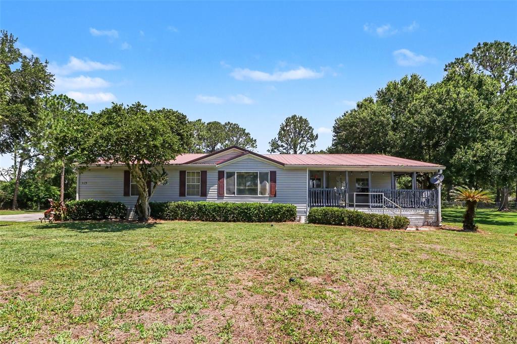 A single-story house with light siding and a red metal roof sits on a lawn — 5105 STAR LINE DRIVE, ST CLOUD, FL